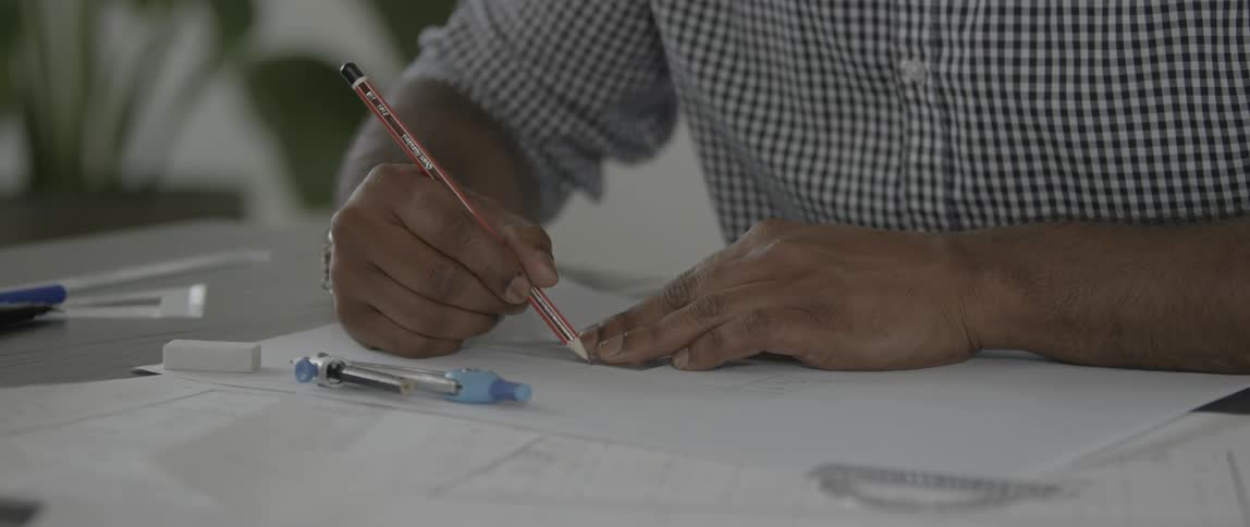 A man uses a pencil and a triangle protractor to draw a line