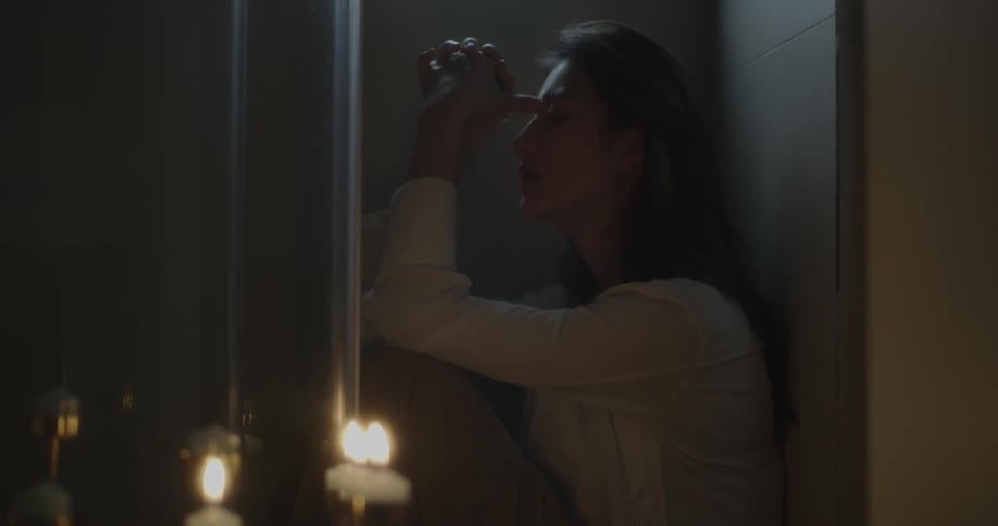 A woman sits in a shower stall with her clothes on