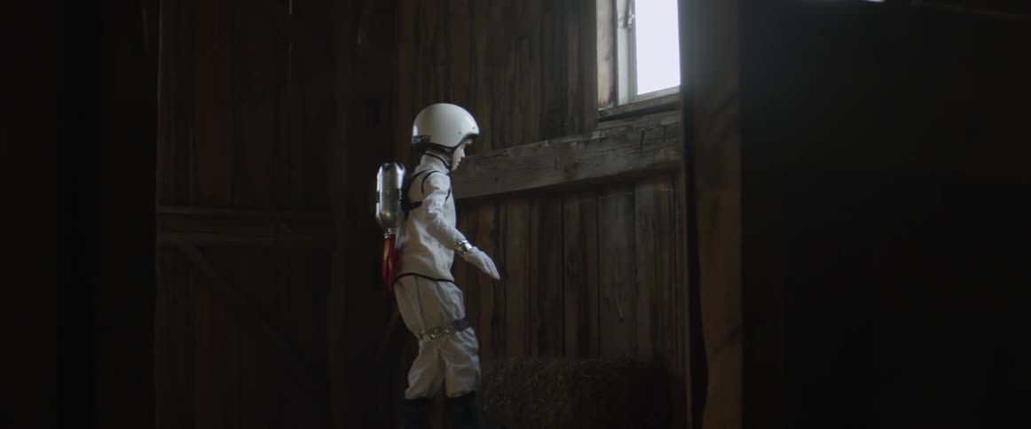 A child wearing a space costume climbs up to a window sill