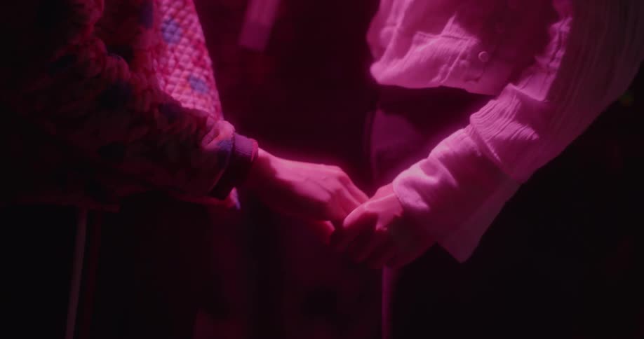 A man and woman hold hands while singing karaoke
