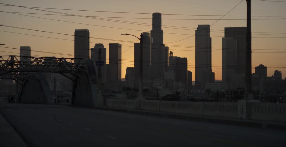 The sun is setting behind the tall buildings ahead
