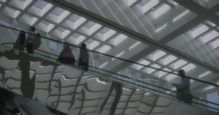 People are riding an escalator in both up and down directions