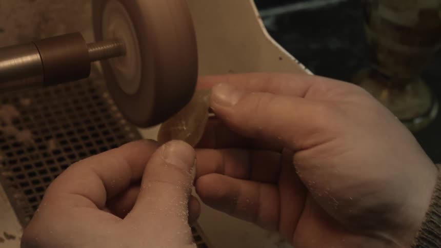 A person grinds a fish carving with a power tool