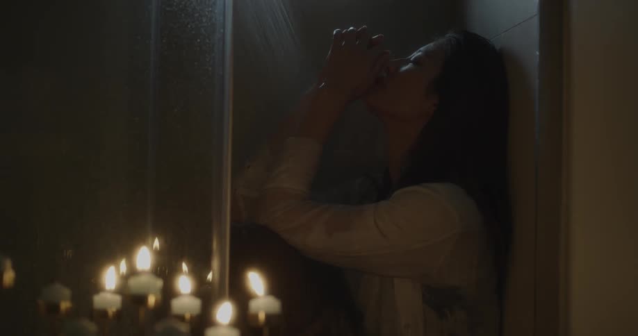 A woman is showering in the dark with candles outside
