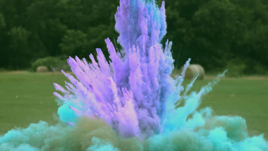 Purple and blue powder explode in the middle of a field