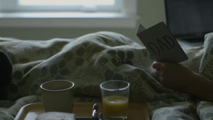 A person is in bed with a tray and holding a card