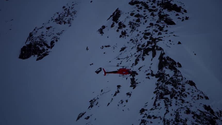 Helicopter flying low above snowy mountains