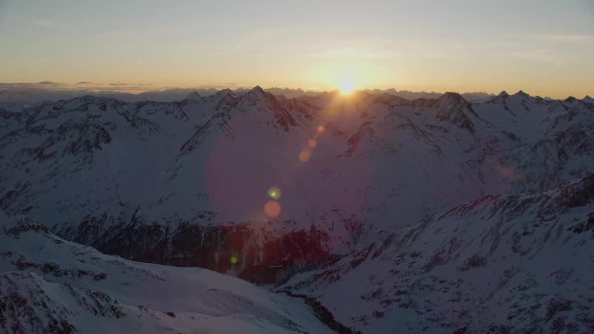 The sun sets over snowy mountains