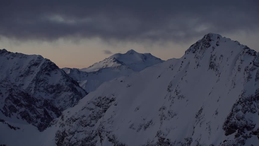 Clouds over snow covered mountain peaks