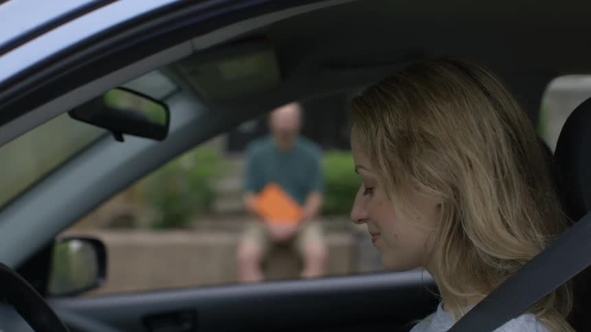 A woman smiles as she puts on her seat belt