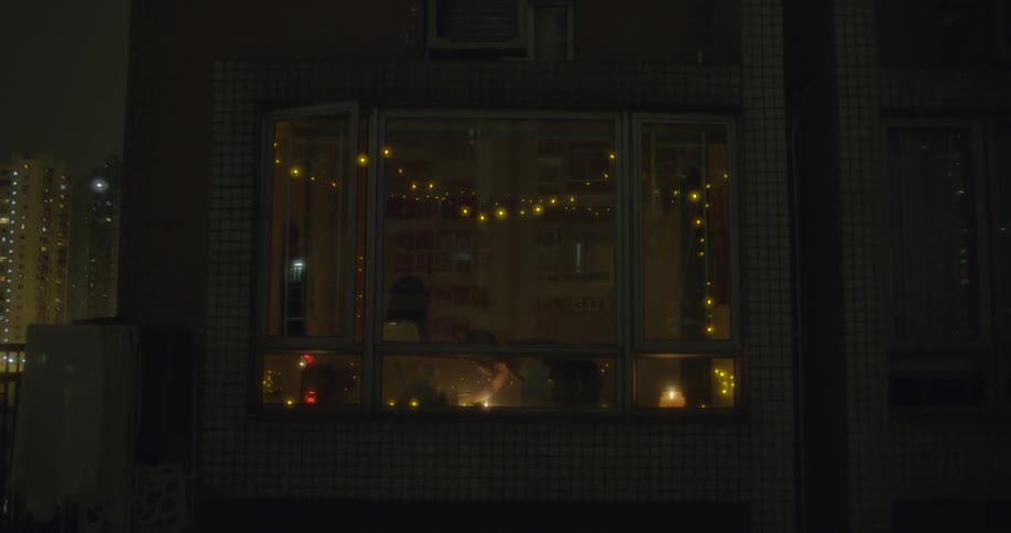 A bay window with lights shows people inside