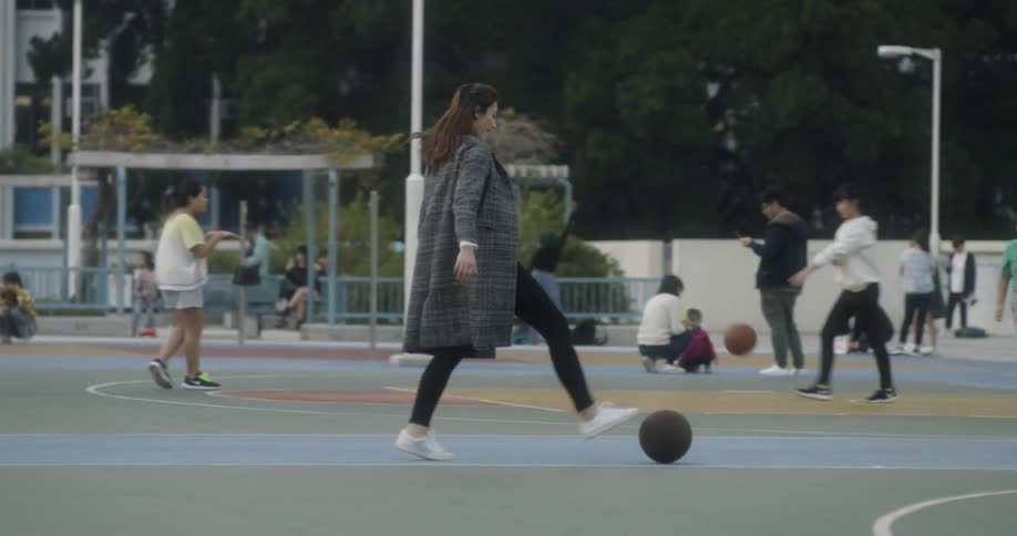 A woman kicks a ball across a playground full of people