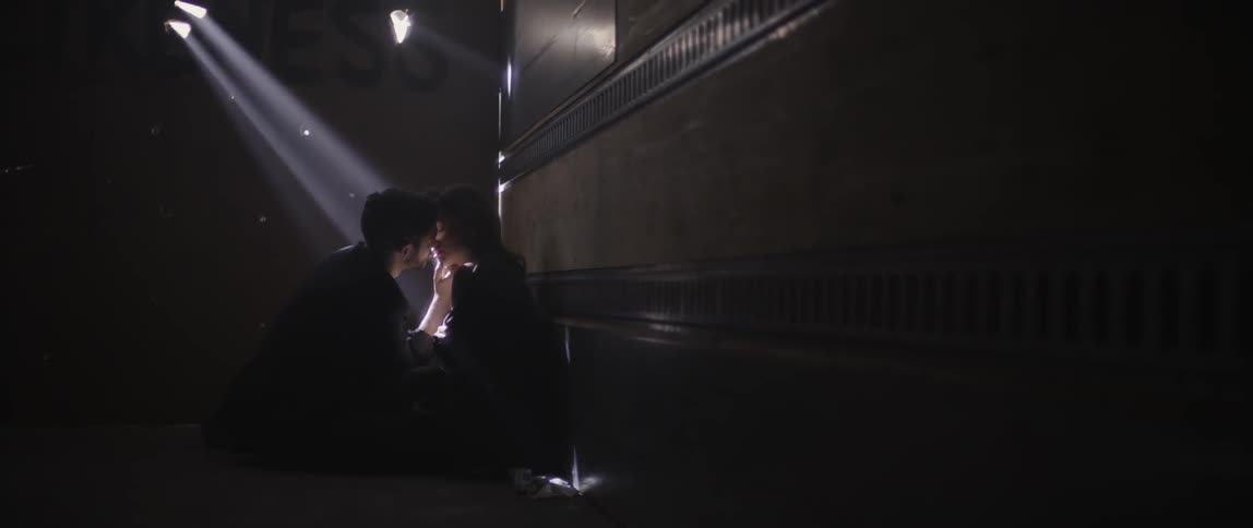 A man and women are making out in a dark hall
