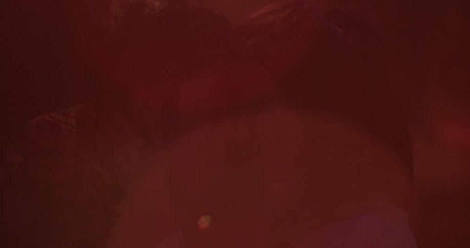 Man and woman resting their heads together in room with flashing lights
