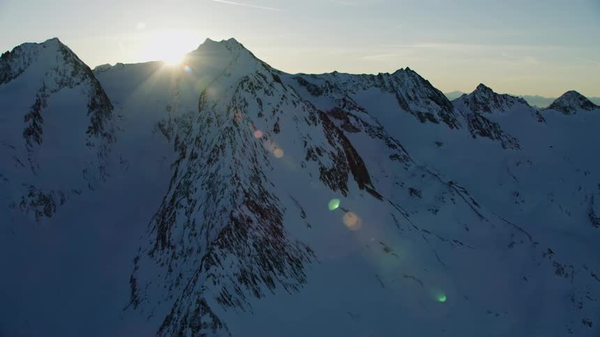 Sun rises over snow covered mountains