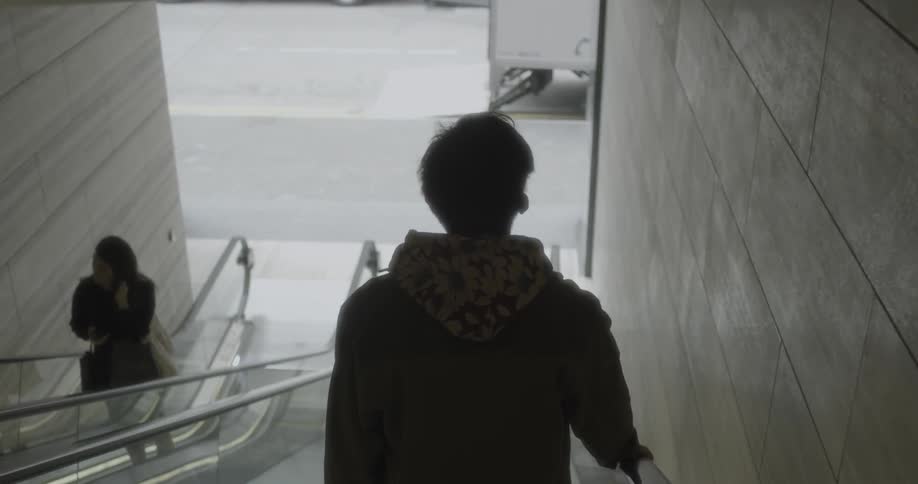 A man is riding an escalator down the hall
