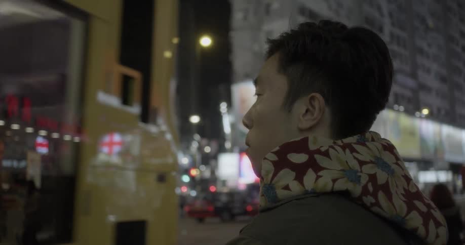 A bus drives by a man standing at an intersection in a city