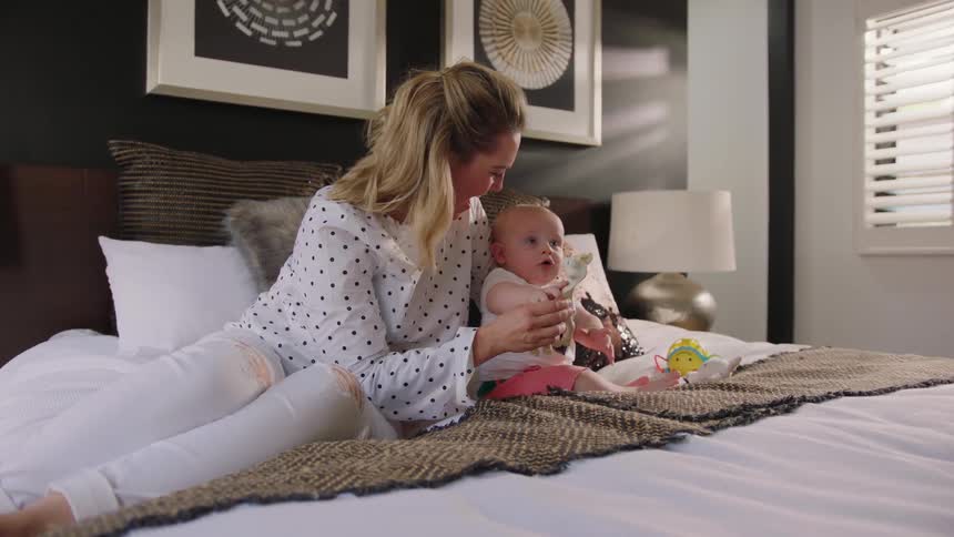 Woman sitting on a bed playing with a baby