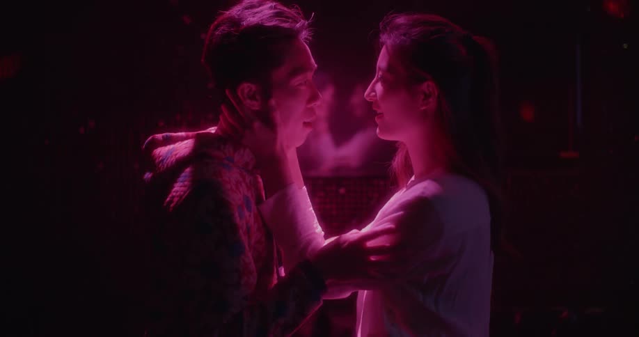 A man and woman embrace in a dark room