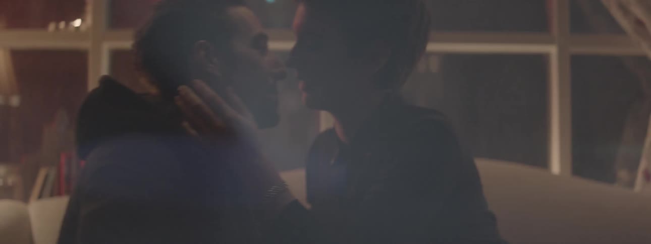 A man and woman kiss on a couch