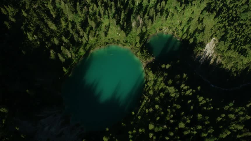 Small emerald colored lakes in between forest of trees