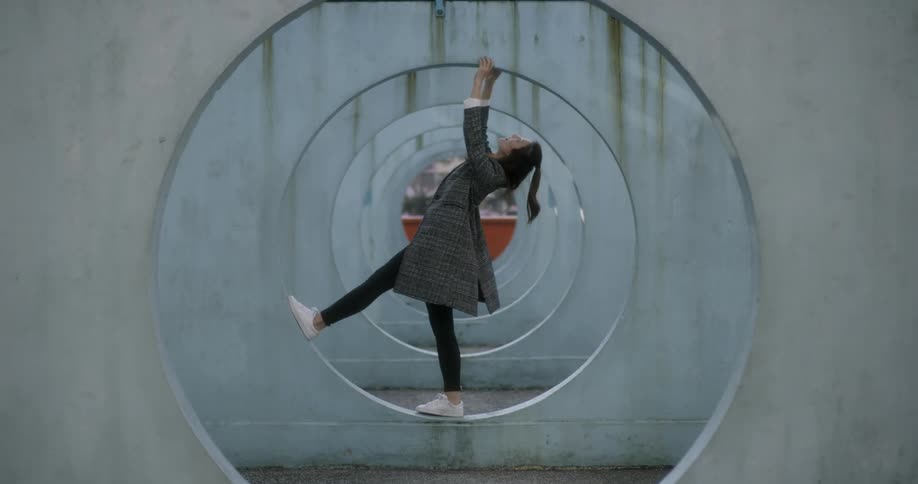 A woman stands in a round opening and leans back