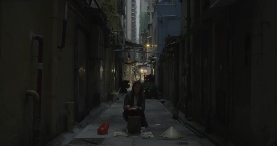 A woman is lighting a fire in a trash bin