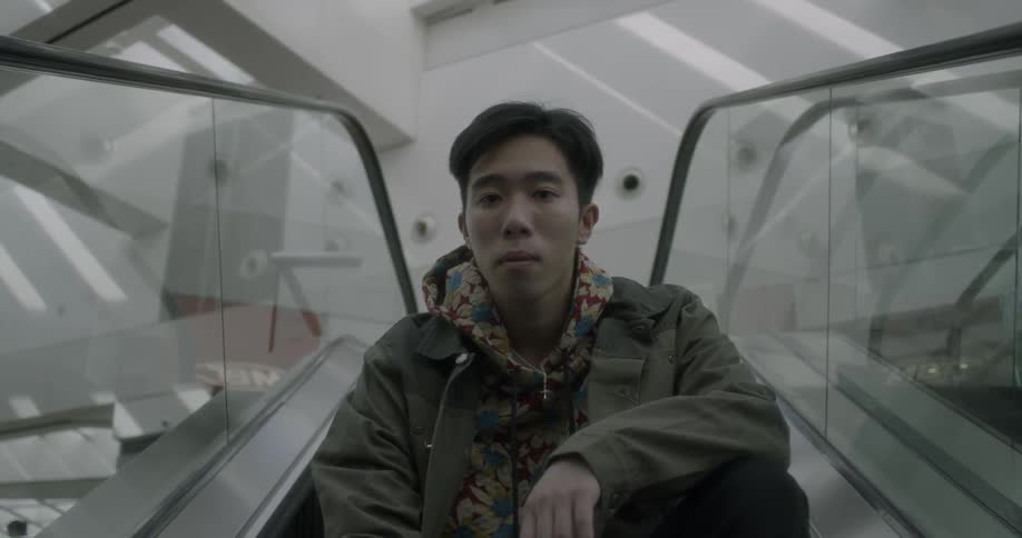 A man rides an escalator while seated