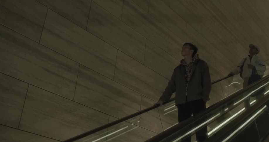 Two people ride the escalator down the dark hall