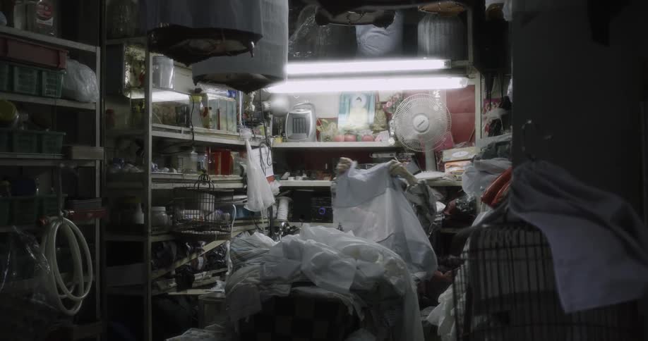 A woman sorts through a pile of fabric in a small shop