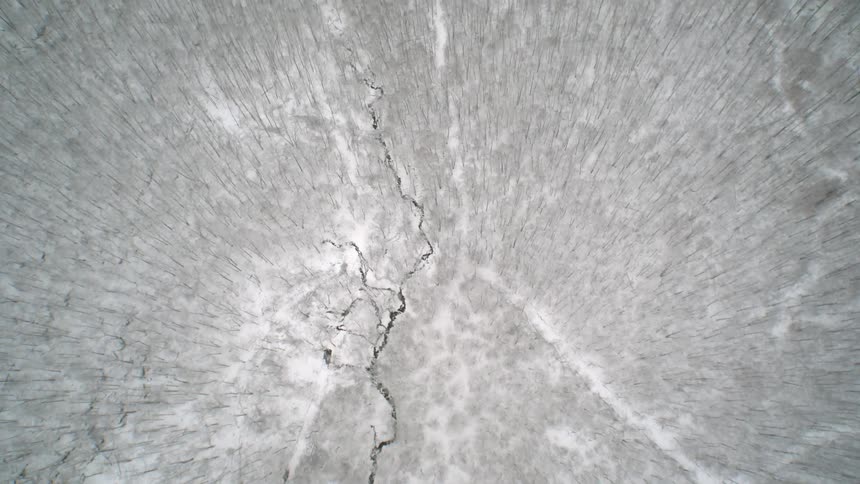 The field below is covered with snow and has a stream running through the middle