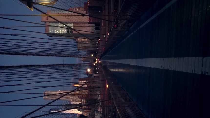 People travel across a bridge towards the city at dawn