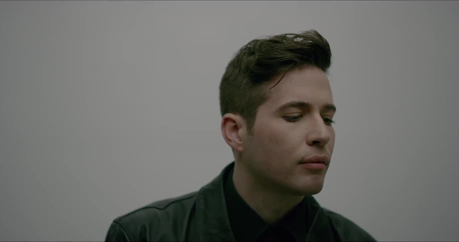 A man wearing black looks down briefly