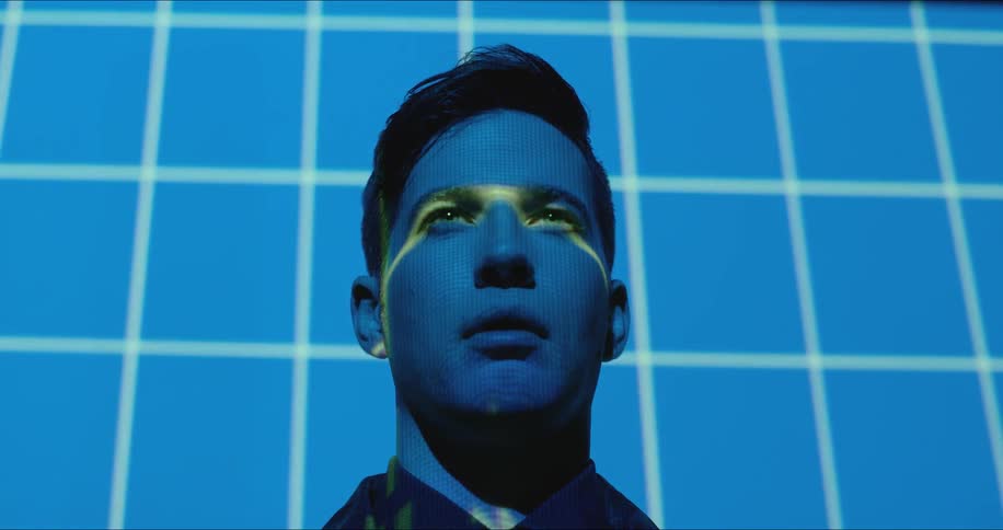 Blue squares and lines are projected onto a man's face and wall