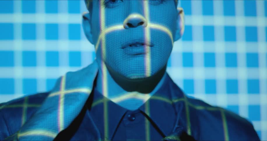 A man rubs his neck as lights flash on him