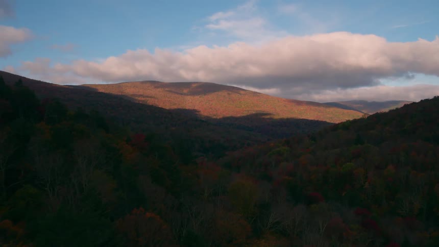 The valley is almost completed covered in shade with clouds in the distance