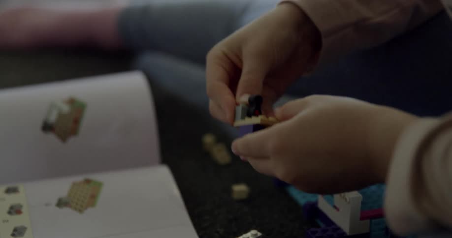 A child is playing with legos on the carpet