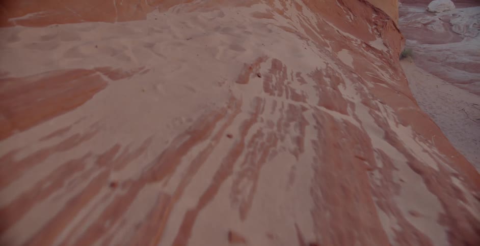 A red rock formation is covered in sand in the desert