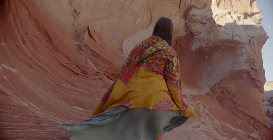 Woman outdoors with colorful clothing blowing in the wind in a rocky area