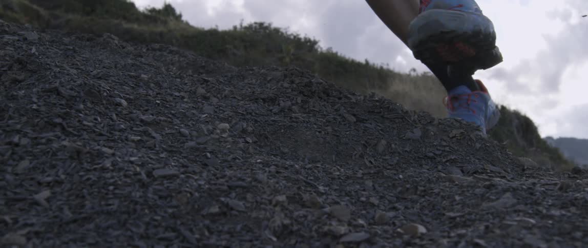 A person is running on a hillside over rocks