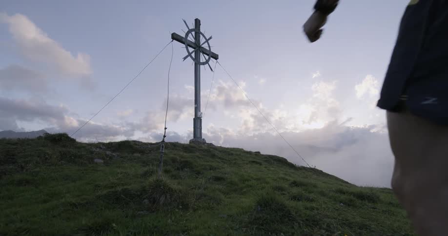 A man runs towards a cross on a mountain
