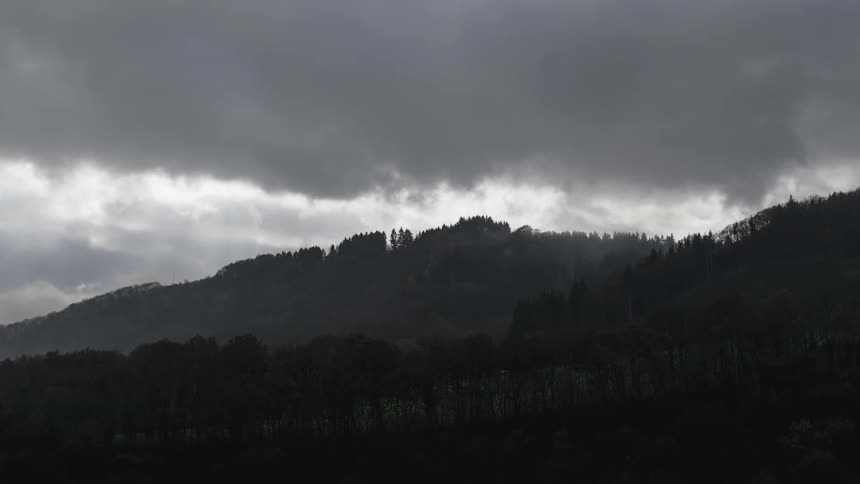 Clouds above a mountain lined with trees