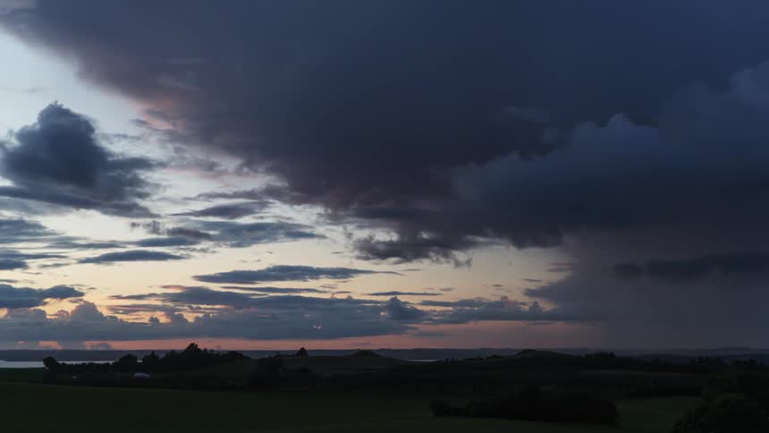 Rain clouds move over the field at sunset