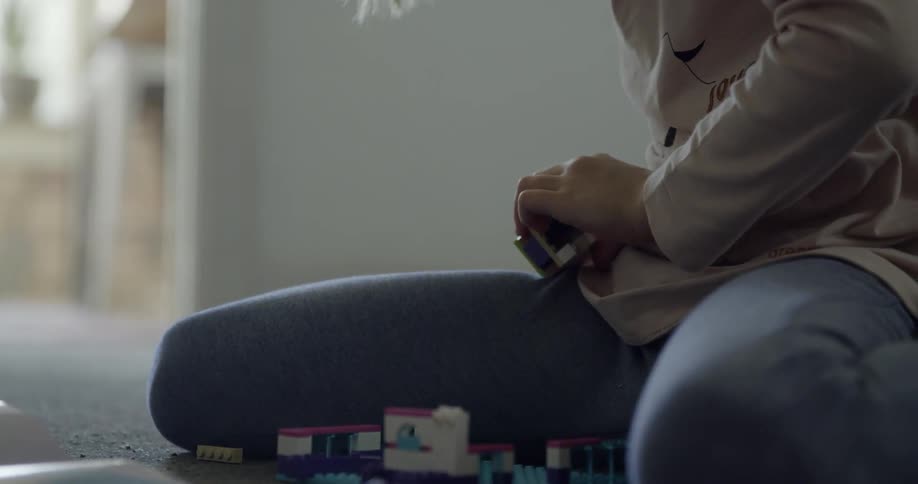 A girl sits on the floor and plays with legos
