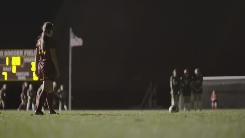 Soccer players are standing around on the field at night