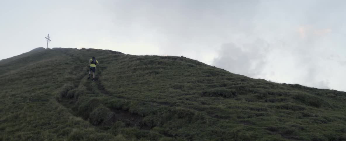 Man jogs up a grassy mountain