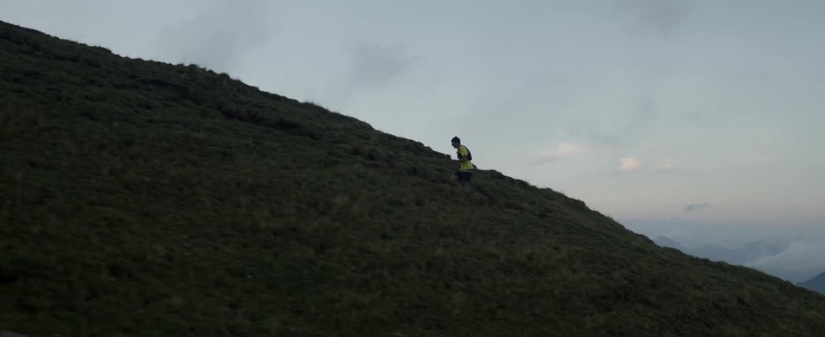 A man is jogging up a steep hill in the morning