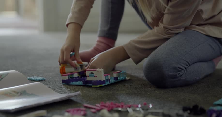 A child sitting on a carpet plays with lego blocks