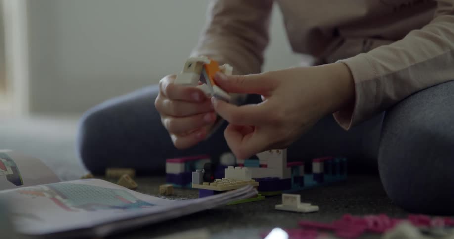 A young girl is using lego-style blocks to build something