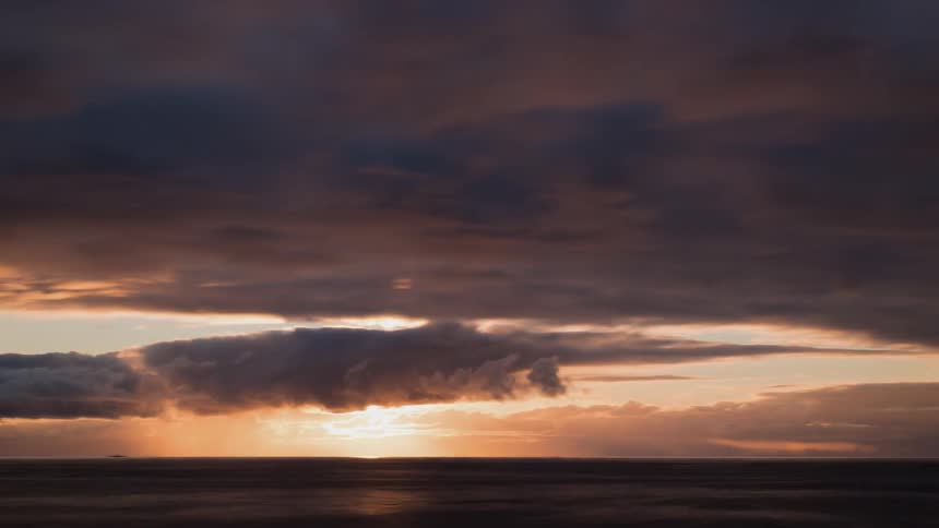 Clouds float over the ocean at sunset